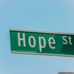 a green street sign hanging from the side of a building